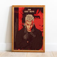 the lost boys movie poster is displayed in a wooden frame on a wood floor next to a white wall