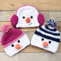 three crocheted hats with pom - poms on them sitting on a wooden surface