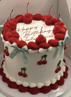 a white and red birthday cake with cherries on it