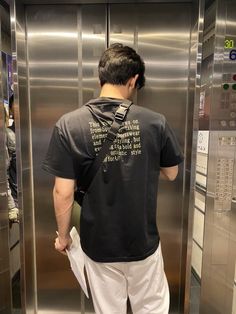 a man standing in front of an elevator with his back to the camera and looking at something