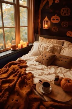 a bed with pumpkins and candles in the window sill, along with a cup of coffee