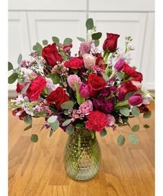 a vase filled with red and pink flowers on top of a wooden table