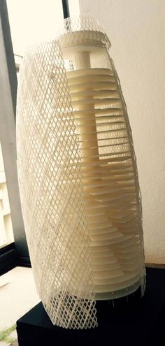 a large white vase sitting on top of a black table next to a window in a room