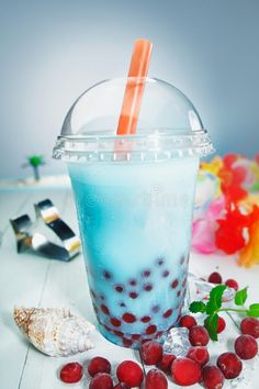 a drink with ice and cherries in it on a white table next to other items