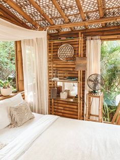 a white bed sitting under a bamboo roof