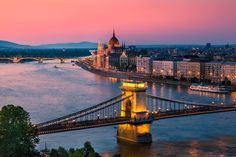 an image of a bridge that is going over the water at sunset or dawn in europe