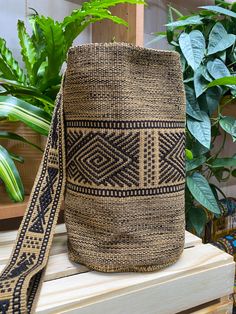 a brown and black bag sitting on top of a wooden bench next to a potted plant