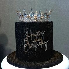 a black birthday cake with a tiara on top and happy birthday written on it