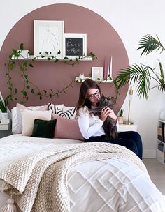 a woman sitting on a bed holding a cat