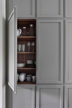 an open cabinet with dishes and cups in it