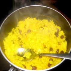 a pot filled with yellow rice on top of a stove