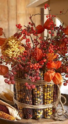 a basket filled with lots of different types of flowers and berries on top of a wooden table