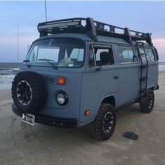 a blue van parked on top of a sandy beach