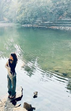 a woman standing on the edge of a body of water