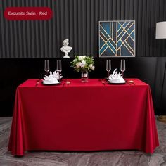 a red table cloth with white napkins and flowers on it in front of a black wall