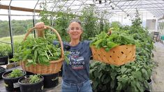 a woman holding two baskets filled with green plants