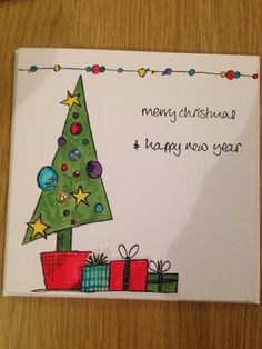 a handmade christmas card with a tree and presents on the bottom, says merry christmas happy new year