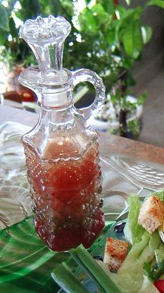 a glass bottle sitting on top of a table next to a plate with salad and dressing