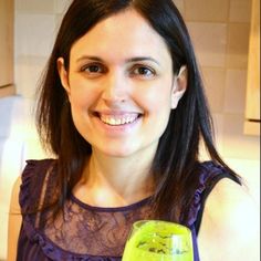 a woman is holding a drink in her hand and smiling at the camera while wearing a purple top