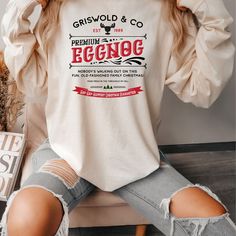 a woman sitting on a chair wearing a white long sleeve shirt with the words, griswold & co