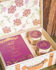 the wedding stationery is in an old suitcase and it's purple and gold