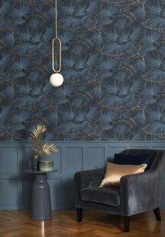 a chair and lamp in front of a blue wall with gold leaf designs on it