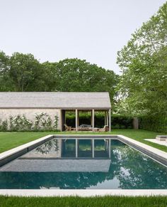 the pool is surrounded by grass and trees