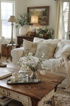 a living room filled with furniture and flowers on top of a coffee table in front of a window