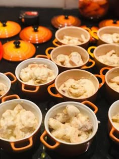 many small bowls filled with food on top of a counter next to orange pumpkins