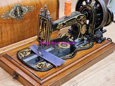 an old fashioned sewing machine sitting on top of a wooden box next to some thread