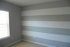 an empty room with gray and white striped walls