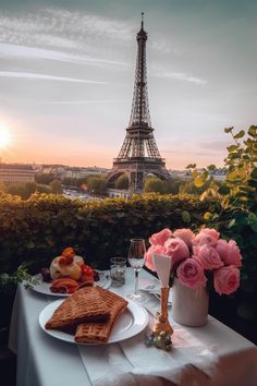 the table is set with food and wine in front of the eiffel tower