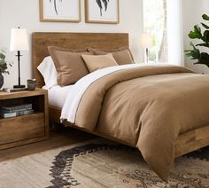 a bed with brown sheets and pillows in a bedroom next to a lamp on a table