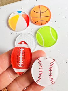 a hand is holding four different colored sports magnets on a white surface with dots and lines