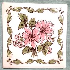 a white and pink flower tile with green leaves on the border, sitting on a blue background