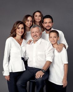 a family posing for a photo with their arms around each other in front of a gray background