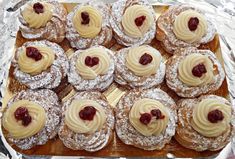 many pastries are arranged on a tray with powdered sugar and jelly toppings