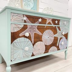 an old dresser painted with sea shells and starfishs on the front, along with seashells