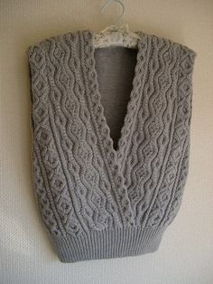 a gray sweater hanging on a wall next to a hanger with an object in it