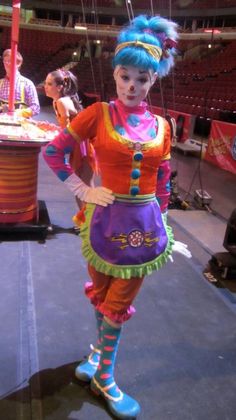 a woman dressed as a clown standing in front of an audience