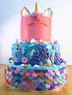 a three tiered cake decorated with sea animals and seashells is on a wooden table