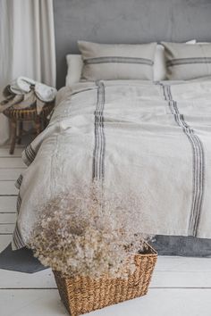 a bed with white linens and a wicker basket on the floor next to it