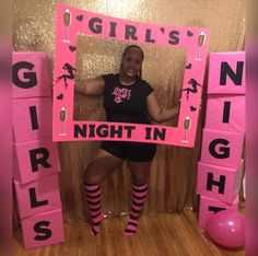 a woman posing in front of a pink sign that says girls night in