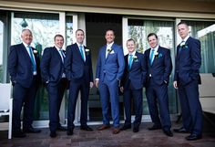 a group of men standing next to each other in front of a door wearing suits