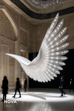 a large white sculpture hanging from the ceiling in a room with people walking around it