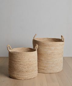 two large baskets sitting on top of a wooden floor next to each other with handles