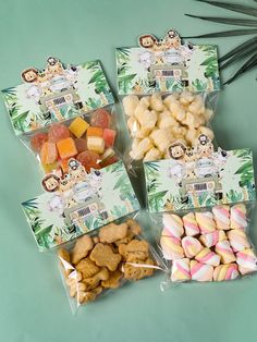 four bags filled with different types of treats on top of a blue tablecloth next to palm leaves