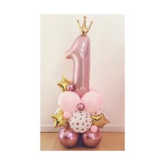 a pink number one balloon sitting on top of balloons in the shape of an animal