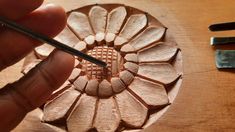 a person is carving a flower with wood shavings