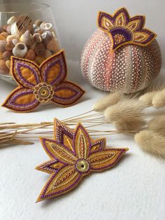 three decorative items are sitting on a table next to some dried grass and pumpkins